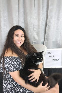 A woman holding a black cat in her arms.
